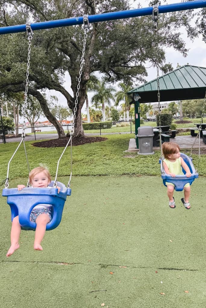 two toddlers swinging at the park