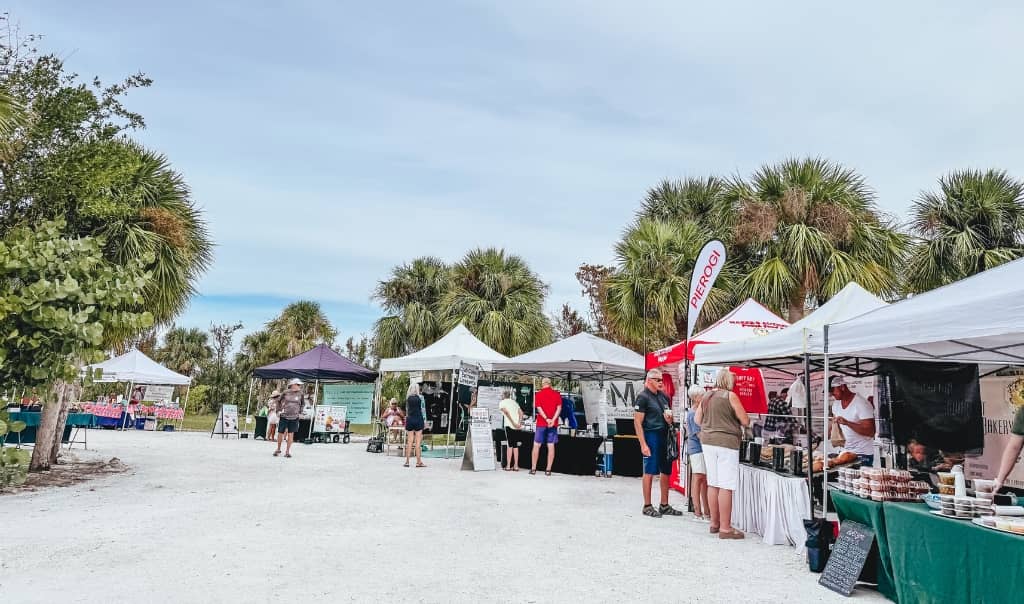 tons of white tents at a farmers market with vendors selling food and customers walking around