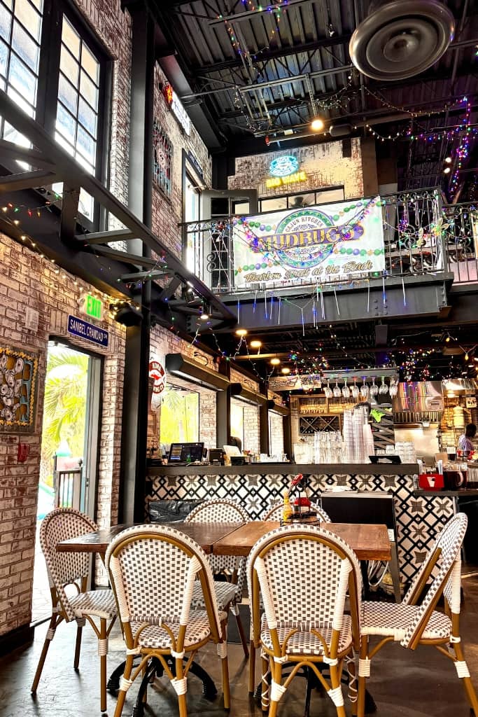 two story restaurant painted black with string lights in vibrant colors with a table and 6 rattan chairs