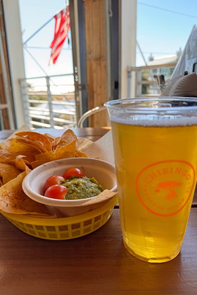 beer, chips, and guacamole at an open air restaurant in santa rosa beach florida overlooking the beach on a sunny day