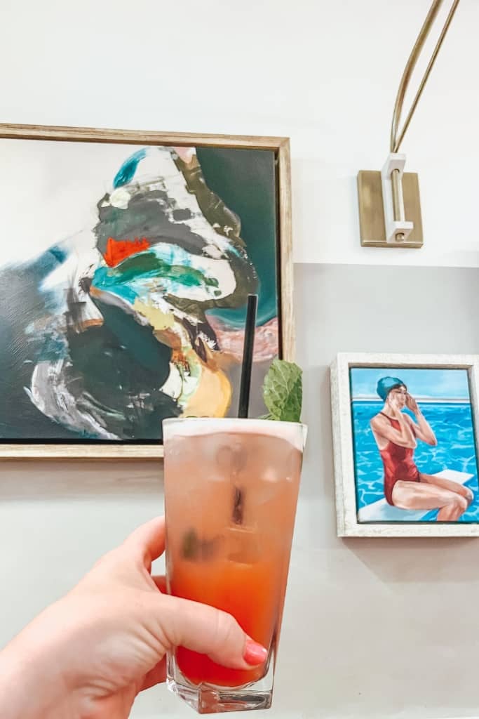 tropical cocktail in front of some beachy pictures at a beach bar