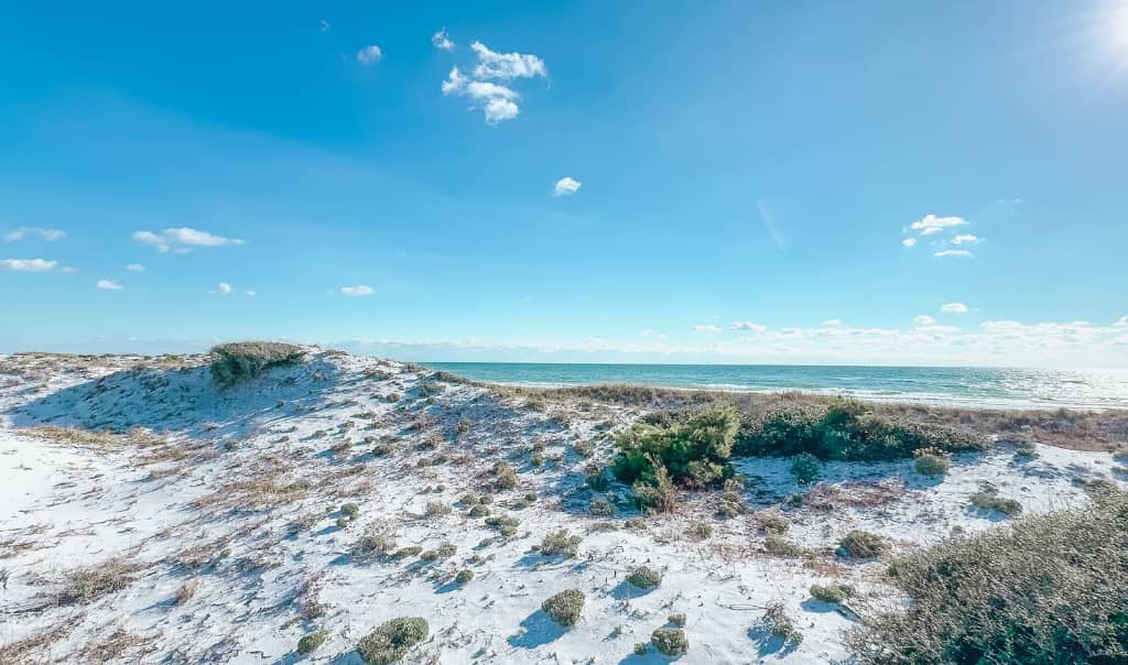 large sand dunes overlooking the beach at topsail hill preserve state park on a sunny day with no clouds