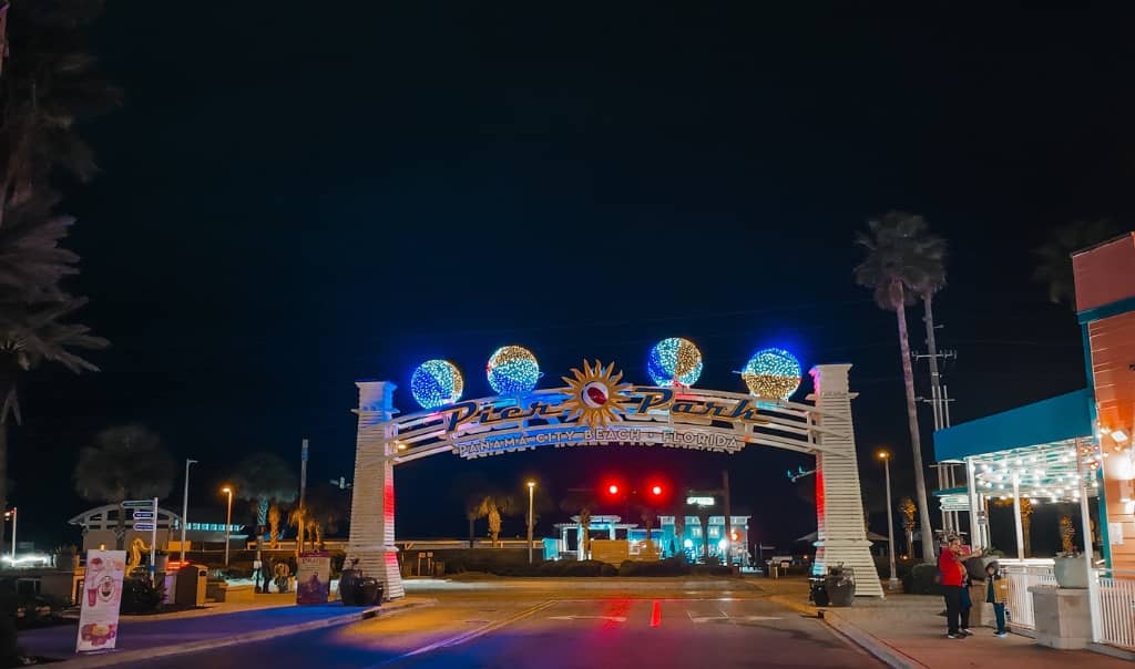 bright colorful arch entry way that says pier park lit up with lights at night time