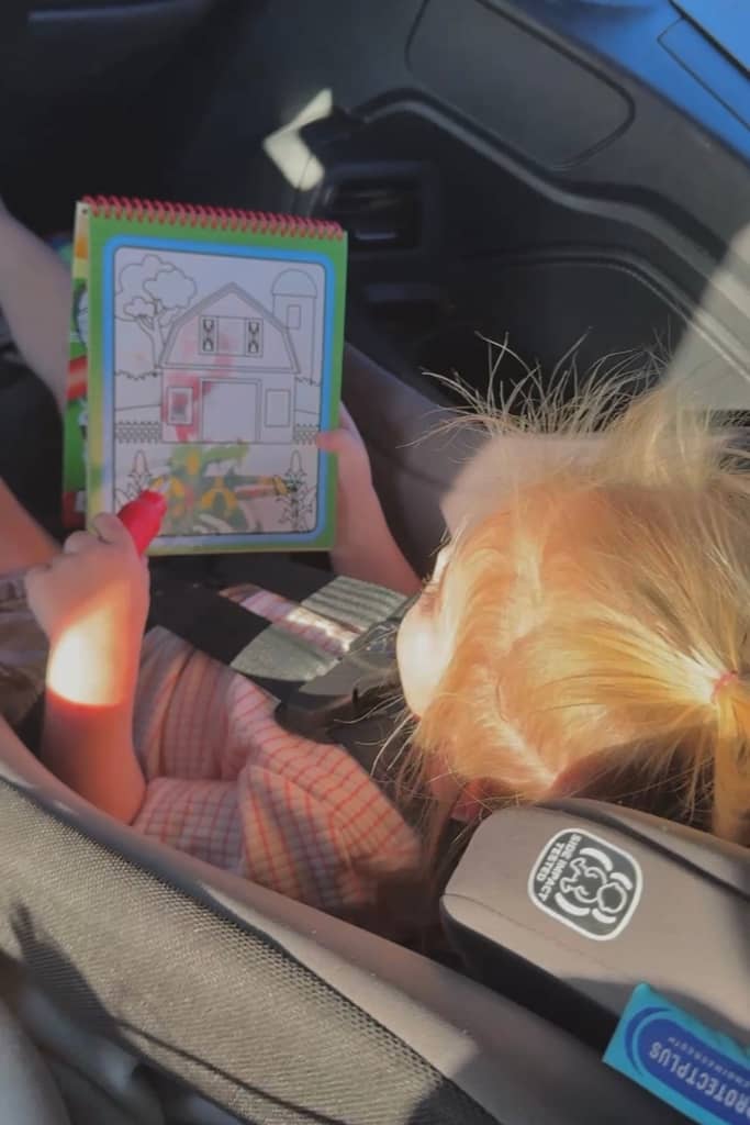 toddler painting with a water wow in a car seat on a road trip