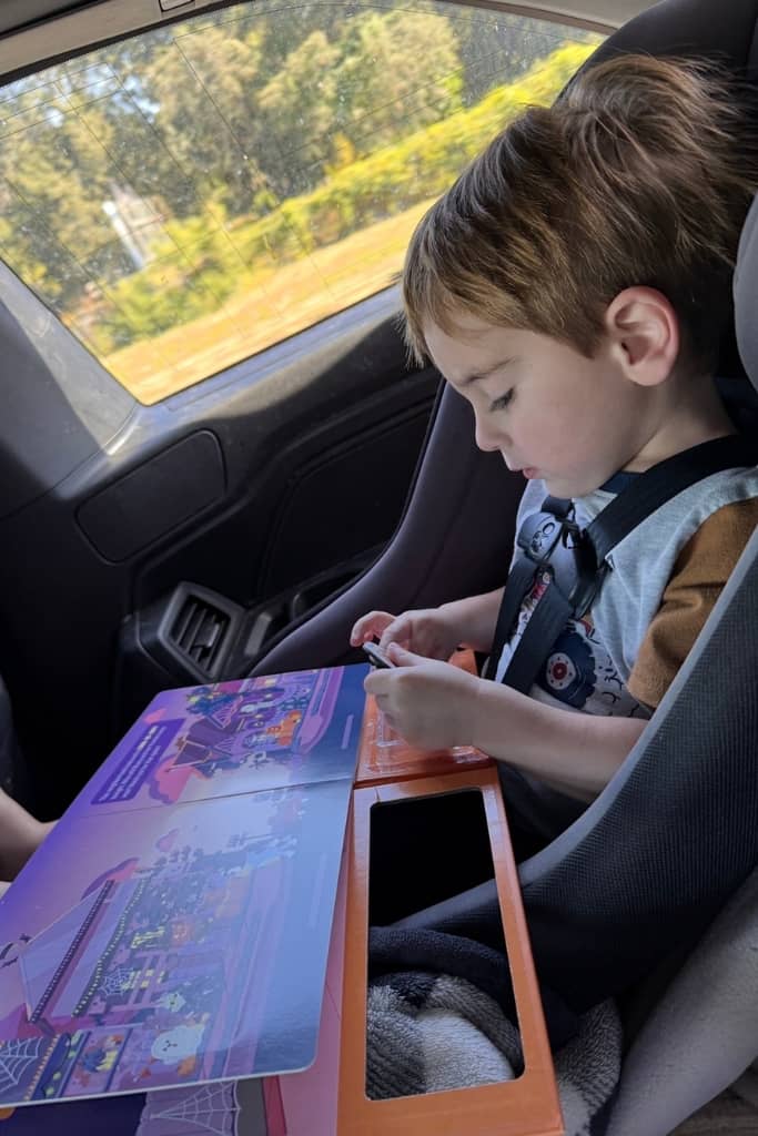 toddler playing with a sticker book on a road trip
