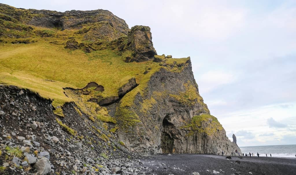Black sand beach with basalt sea stacks and ocean waves at Reynisfjara in Iceland.