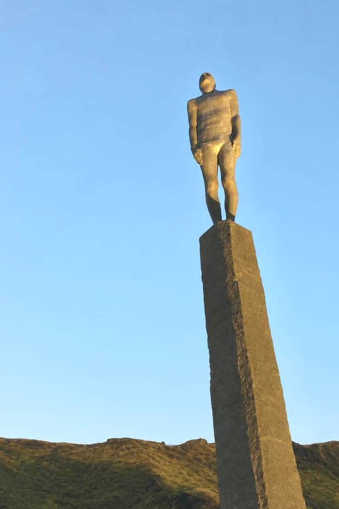 tall statue of a man standing on top of a concrete pillar
