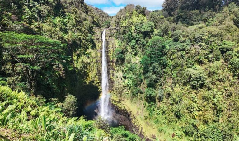 large cascading waterfall surrounded by mountain with green foliage