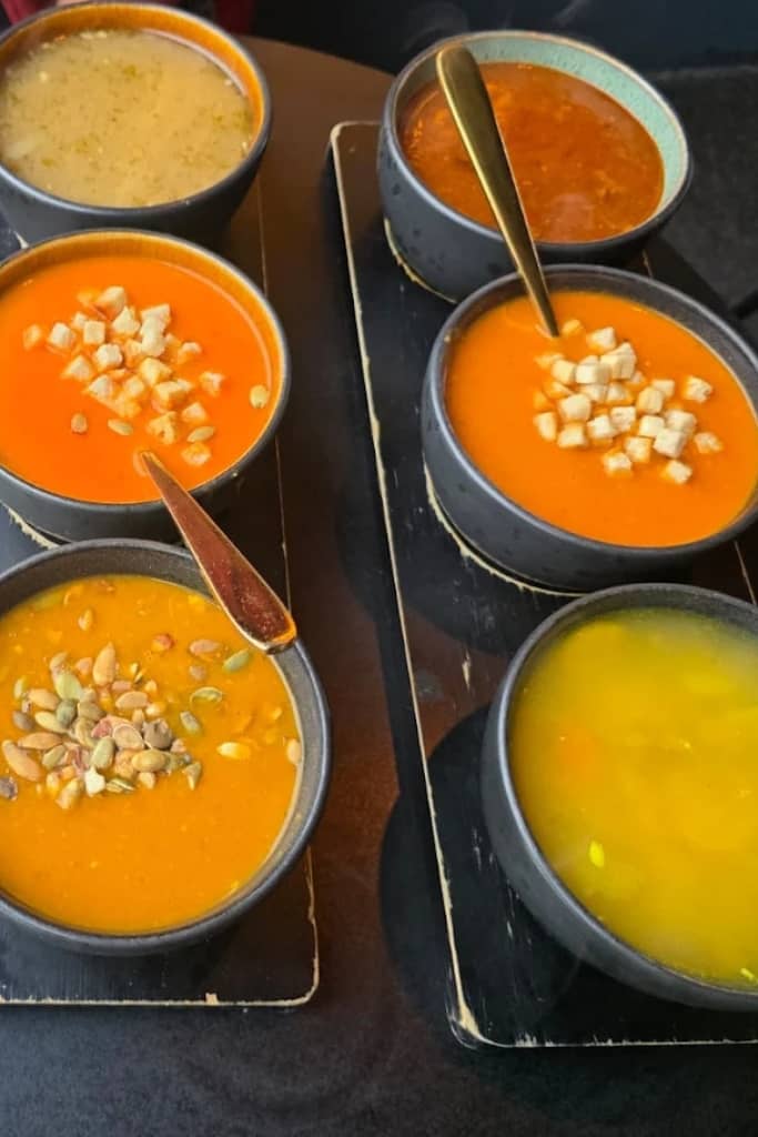 two flights of soup each with three soups, a yellow soup, an orange soup, and a red soup